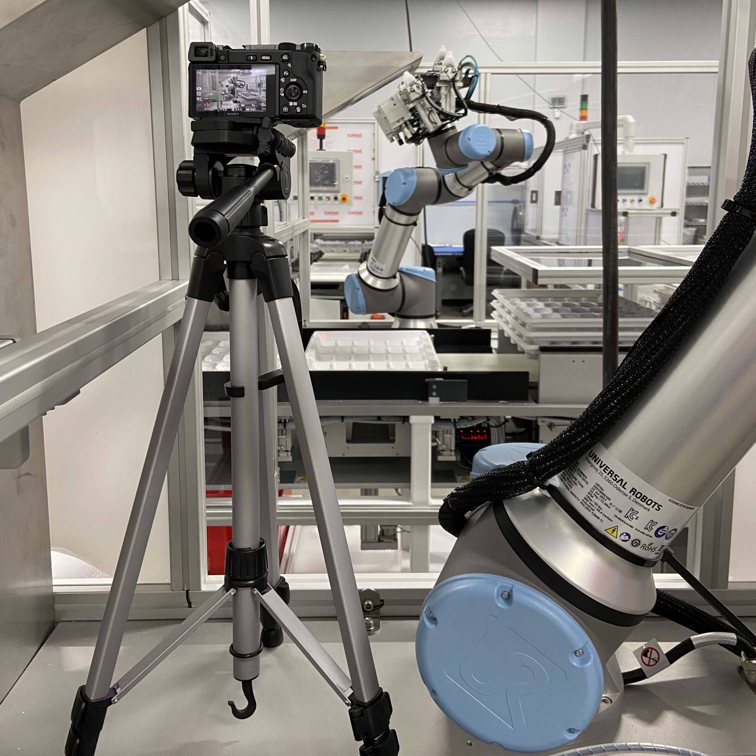 Camera on tripod filming collaborative robot arm
